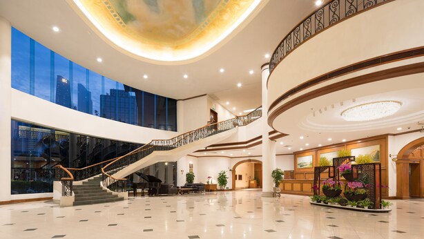Un vestíbulo amplio con una imponente escalera, un piano y una zona de recepción.