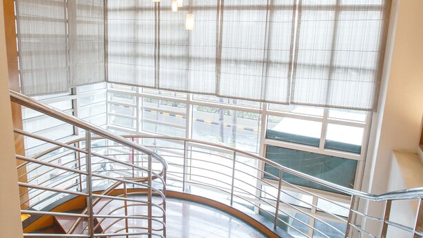 Un interior moderno con una escalera curva, un candelabro y ventanas amplias.