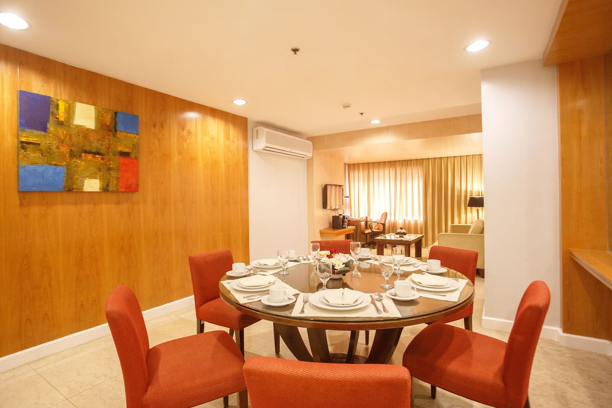 A dining area with a round table set for six, surrounded by orange chairs.