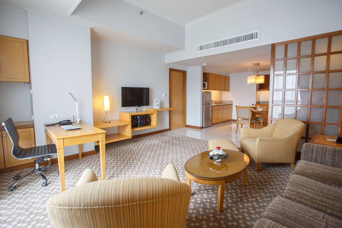 A modern hotel room with a living area, kitchenette, and a dining area.