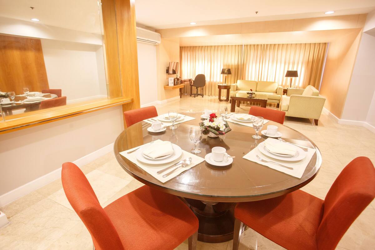A dining area with a round table set for four, surrounded by orange chairs.