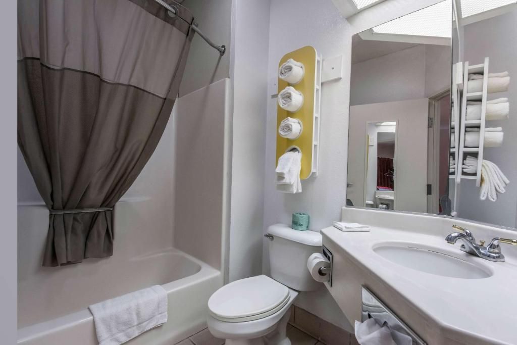 Un baño con bañera, inodoro, lavamanos y un perchero con toallas.
