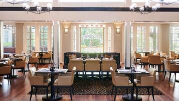A restaurant with a central bar area, multiple dining tables, and chairs.
