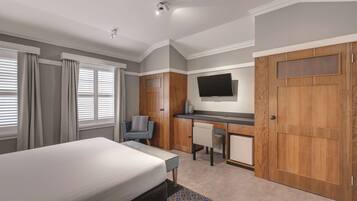 A hotel room with a bed, desk, chair, TV, and wardrobe.