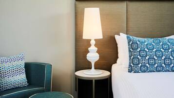 Una camera d'albergo ordinata con un letto, un tavolino con una lampada, un divano e cuscini decorati.