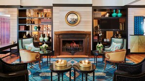 Un rincón acogedor con chimenea, asientos cómodos y una estantería llena de objetos decorativos.
