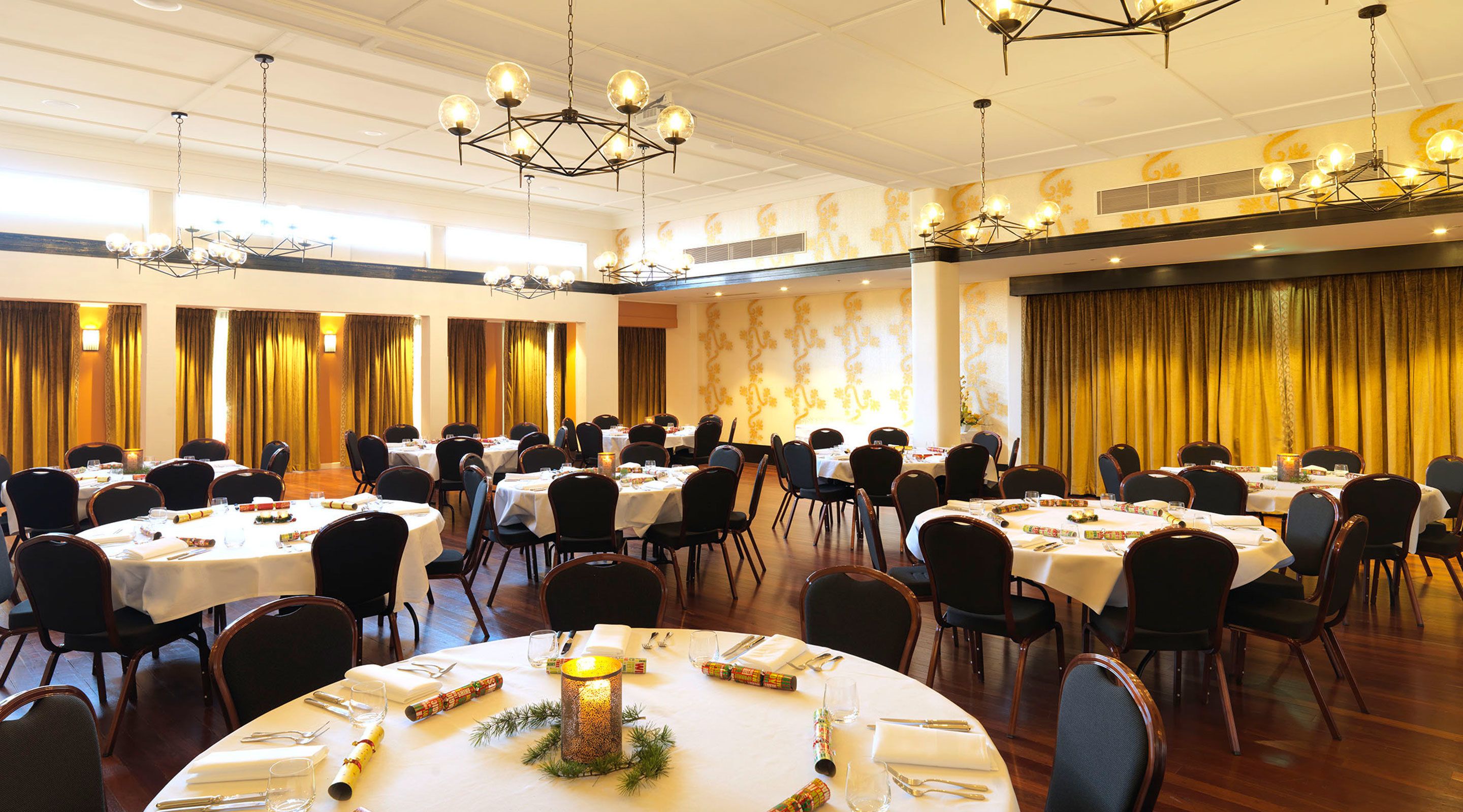 A large banquet hall with round tables set for dining, arranged in rows.