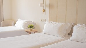 A hotel room with two beds, a small round table with a plant, and a chair. - Hotel Oriente (Zaragoza)