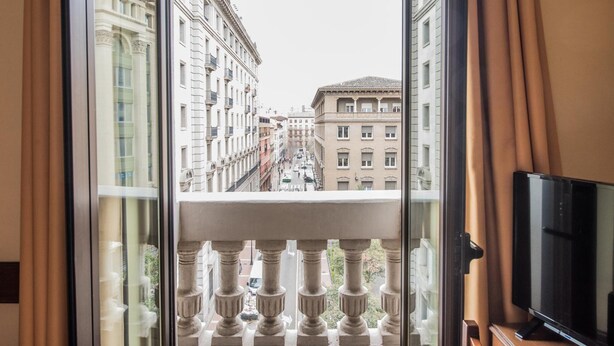 A hotel room with a balcony overlooking a city street. - Hotel Oriente (Zaragoza)