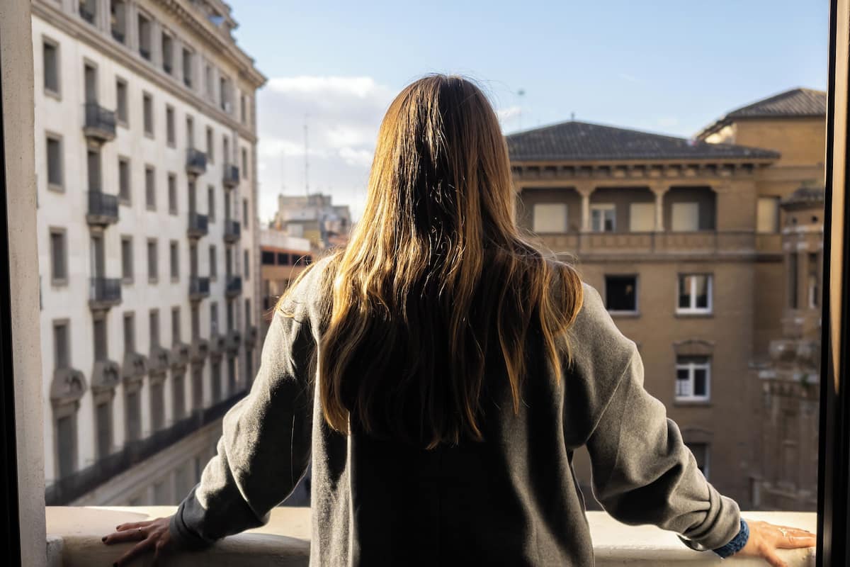 A person standing on a balcony with a view of a cityscape.