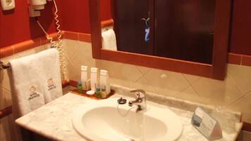 Une salle de bain avec un lavabo blanc, un porte-serviettes avec une serviette, un miroir et un meuble contenant un distributeur de serviettes.