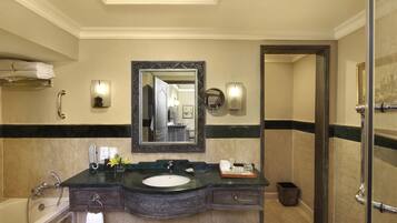 A bathroom with a large mirror, a sink, a vanity, and a bathtub.