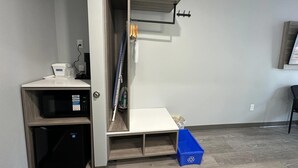 Een compacte kamer met een ingebouwde magnetron, een klein plankje en een blauwe opbergbox.