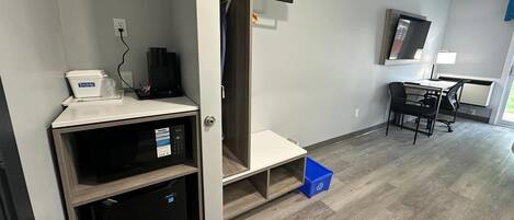 Una habitación pequeña con kitchenette, una mesita y una silla.
