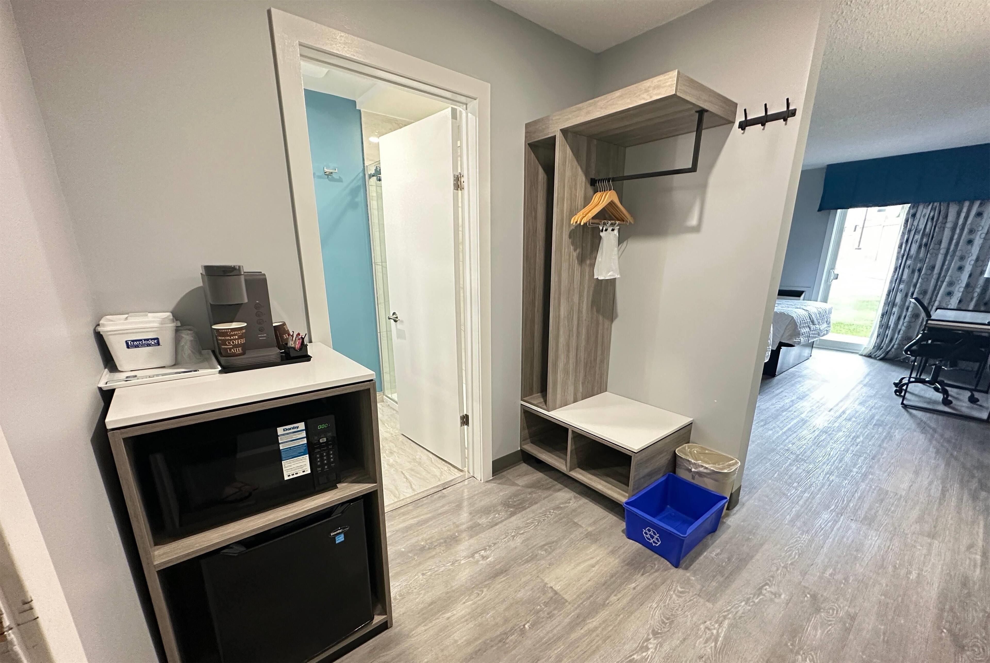Hotelkamer met kitchenette, een klein tafeltje, een kapstok en uitzicht naar buiten.