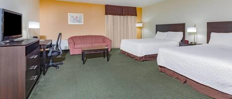 A hotel room with two beds, a desk with a television, a chair, and a small table.