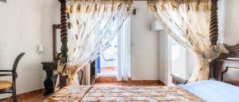 Ein Schlafzimmer mit einem Himmelbett, einem Holztisch und einem Stuhl.