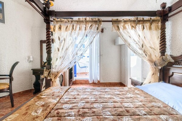 Ein Schlafzimmer mit einem Himmelbett, einem Holztisch und einem Stuhl.