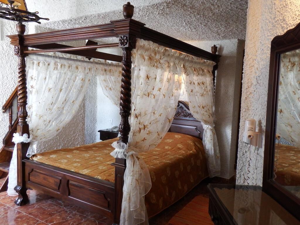 A four-poster bed with a canopy, a wooden nightstand, and a mirror on the wall.