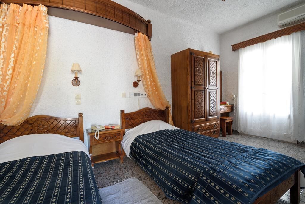 Una camera da letto con due letti, un armadio in legno, un comodino e una finestra con tende.