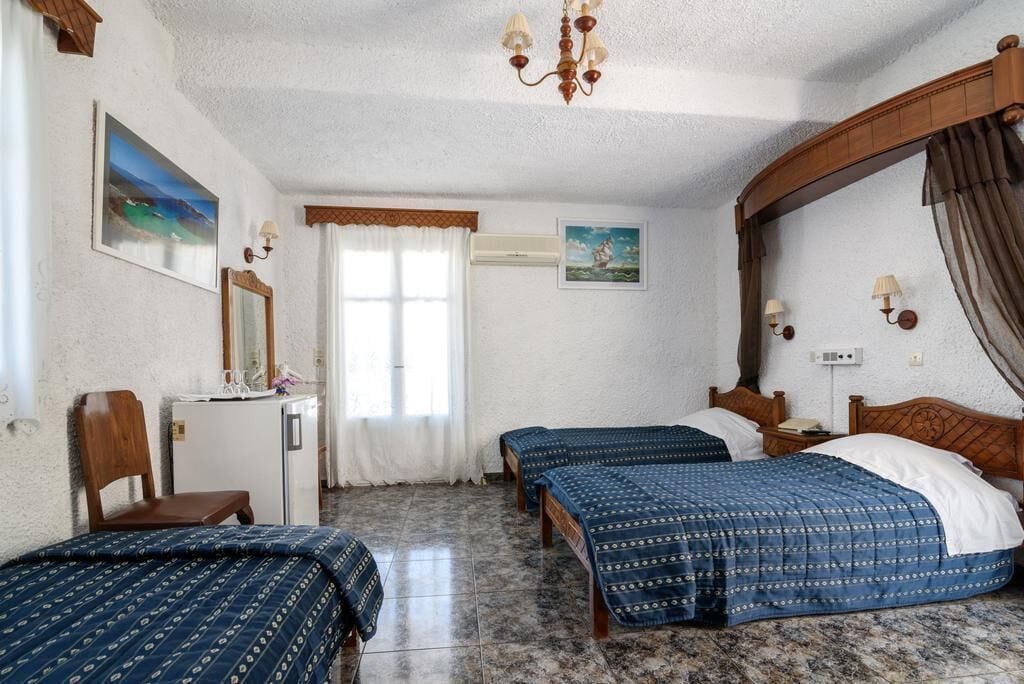Una habitación con dos camas, un escritorio, una silla y un refrigerador pequeño.