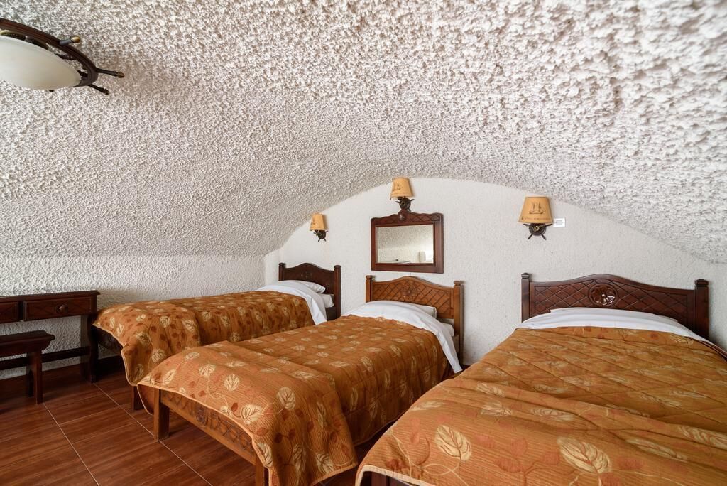 Ein Zimmer mit zwei Betten, Holzkopfteilen und einem kleinen Schreibtisch.