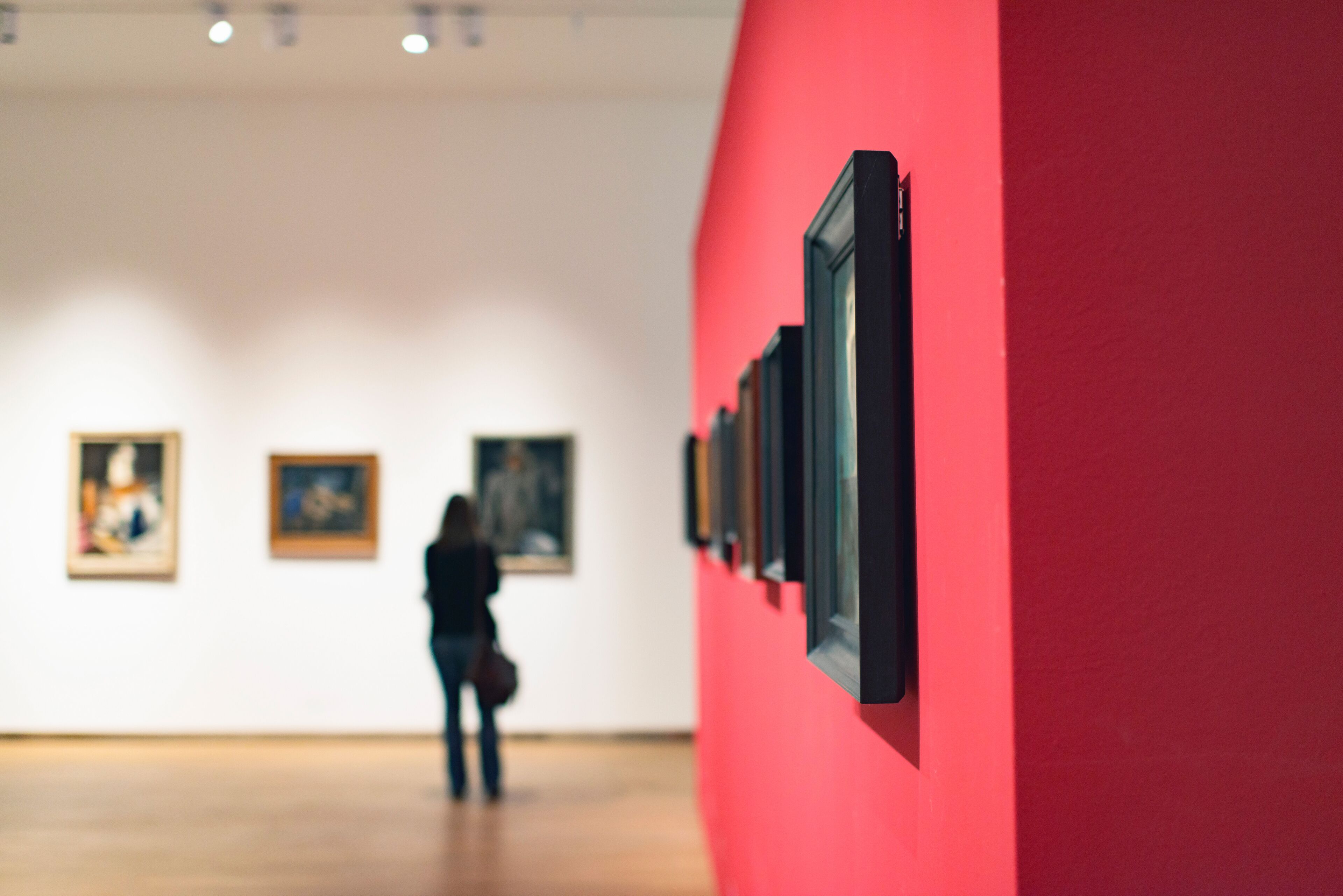 Eine Kunstgalerie mit gerahmten Kunstwerken an der Wand und einem Holzboden.