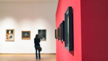 Eine Kunstgalerie mit gerahmten Kunstwerken an der Wand und einem Holzboden.