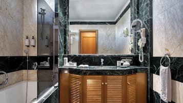 Un baño moderno con tocador de mármol, cabina de ducha de vidrio y puerta de madera.