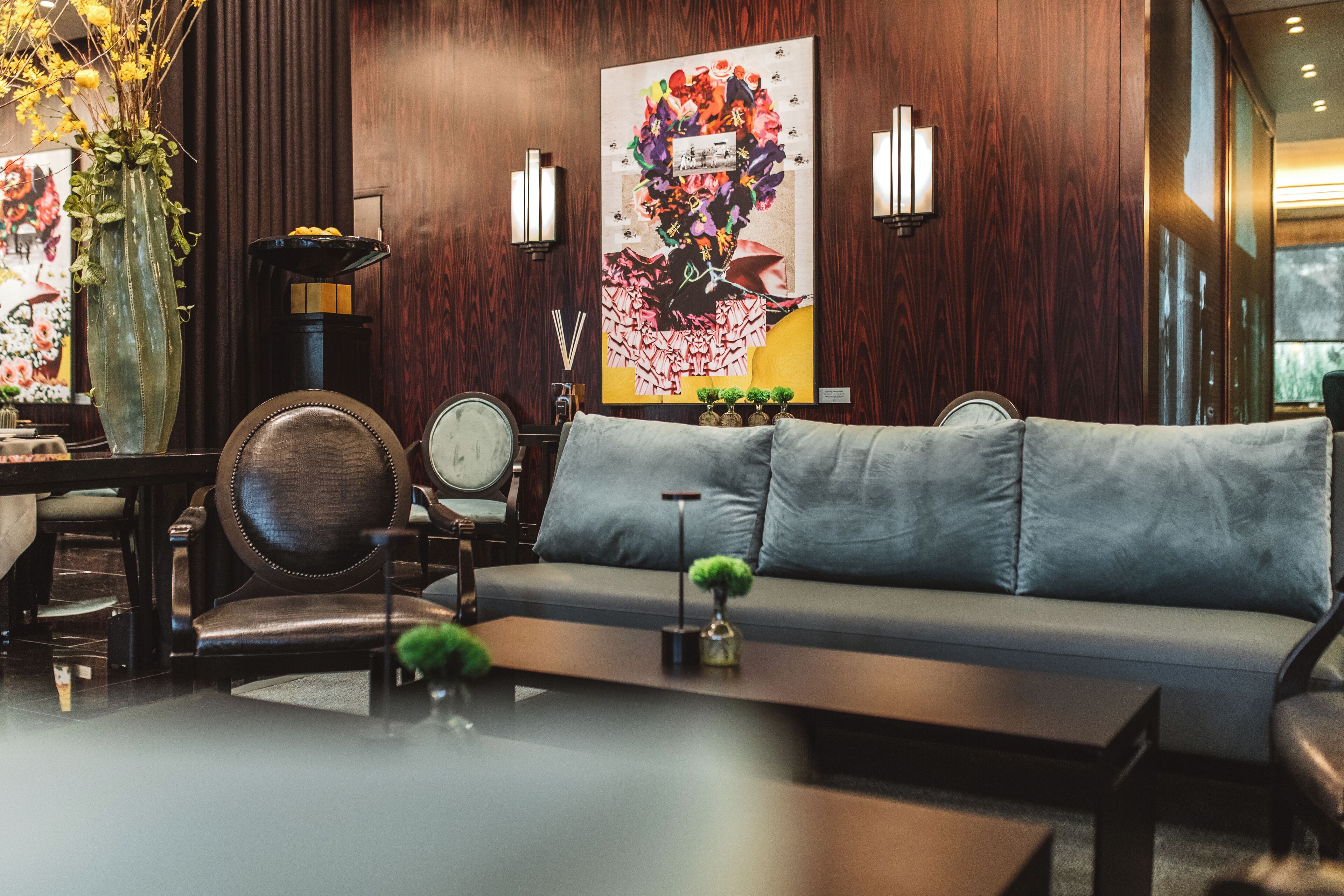 A modern living room with a grey sofa, a wooden coffee table, and a vase with yellow flowers.