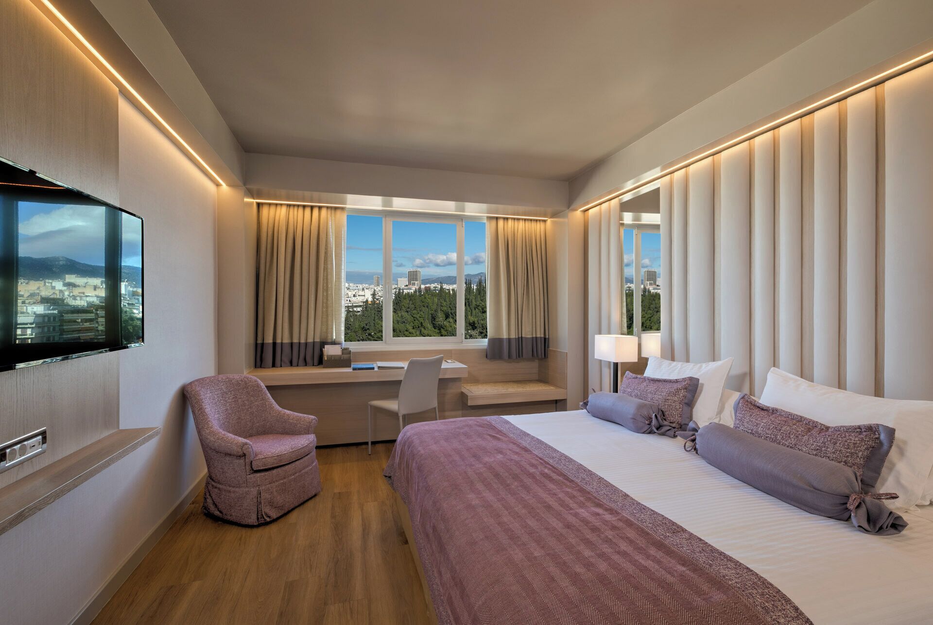 A hotel room with a bed, a desk, a chair, and a TV.