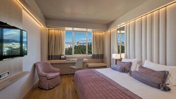 A hotel room with a bed, a desk, a chair, and a TV.