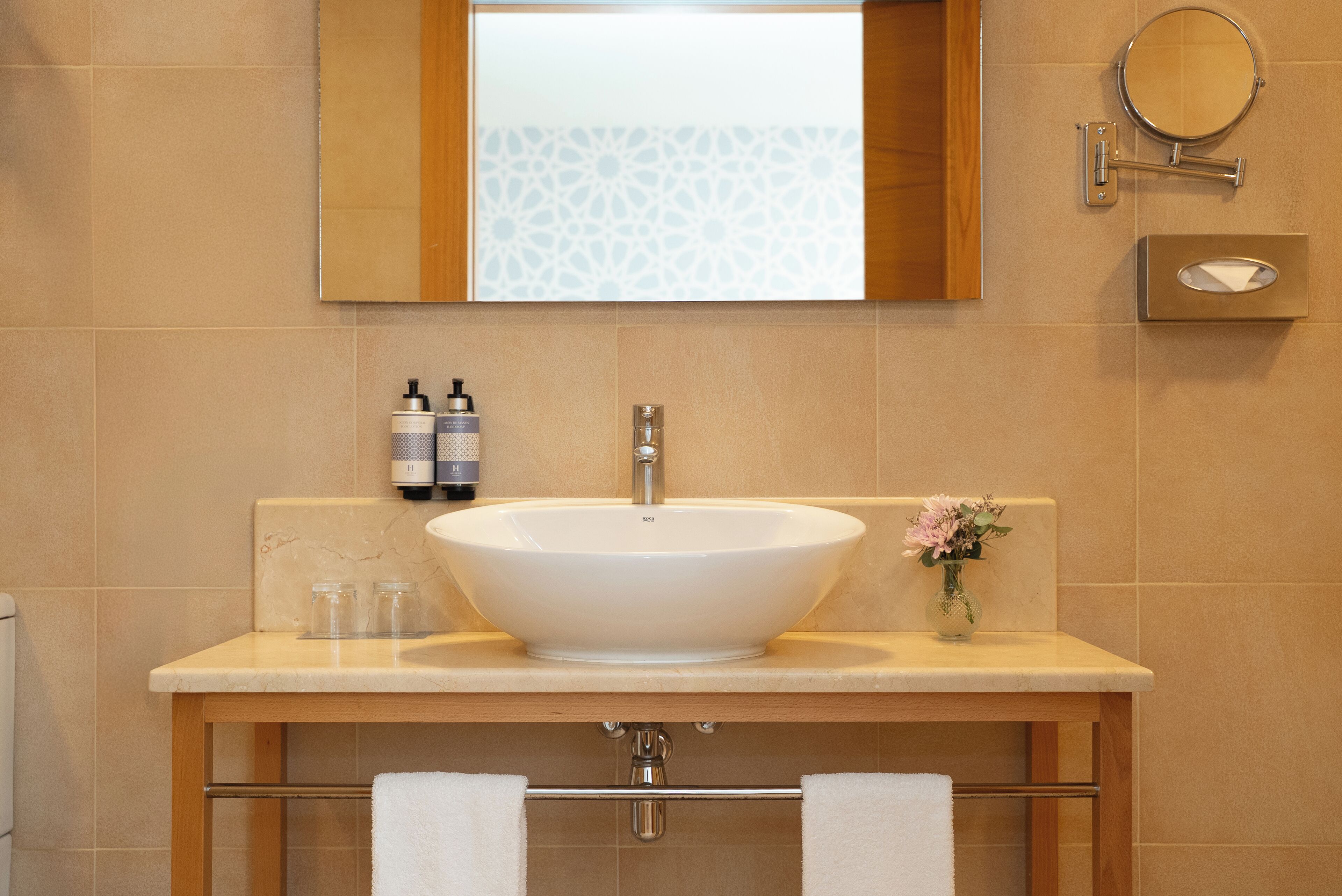 Un baño con un lavamanos grande de color blanco, un espejo y un perchero para toallas.
