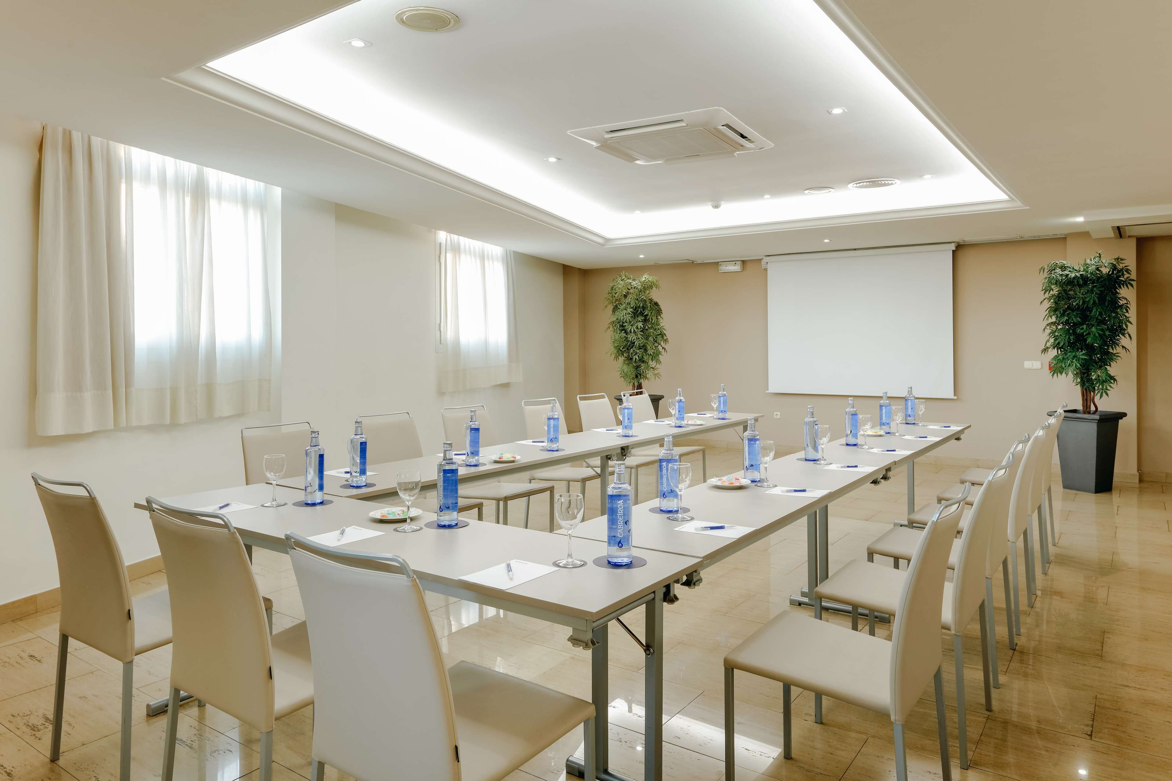 Une salle de conférence équipée d’une longue table, de chaises et d’un écran de projection.