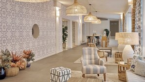 A spacious hallway with patterned wallpaper, wicker furniture, and hanging rattan lamps.