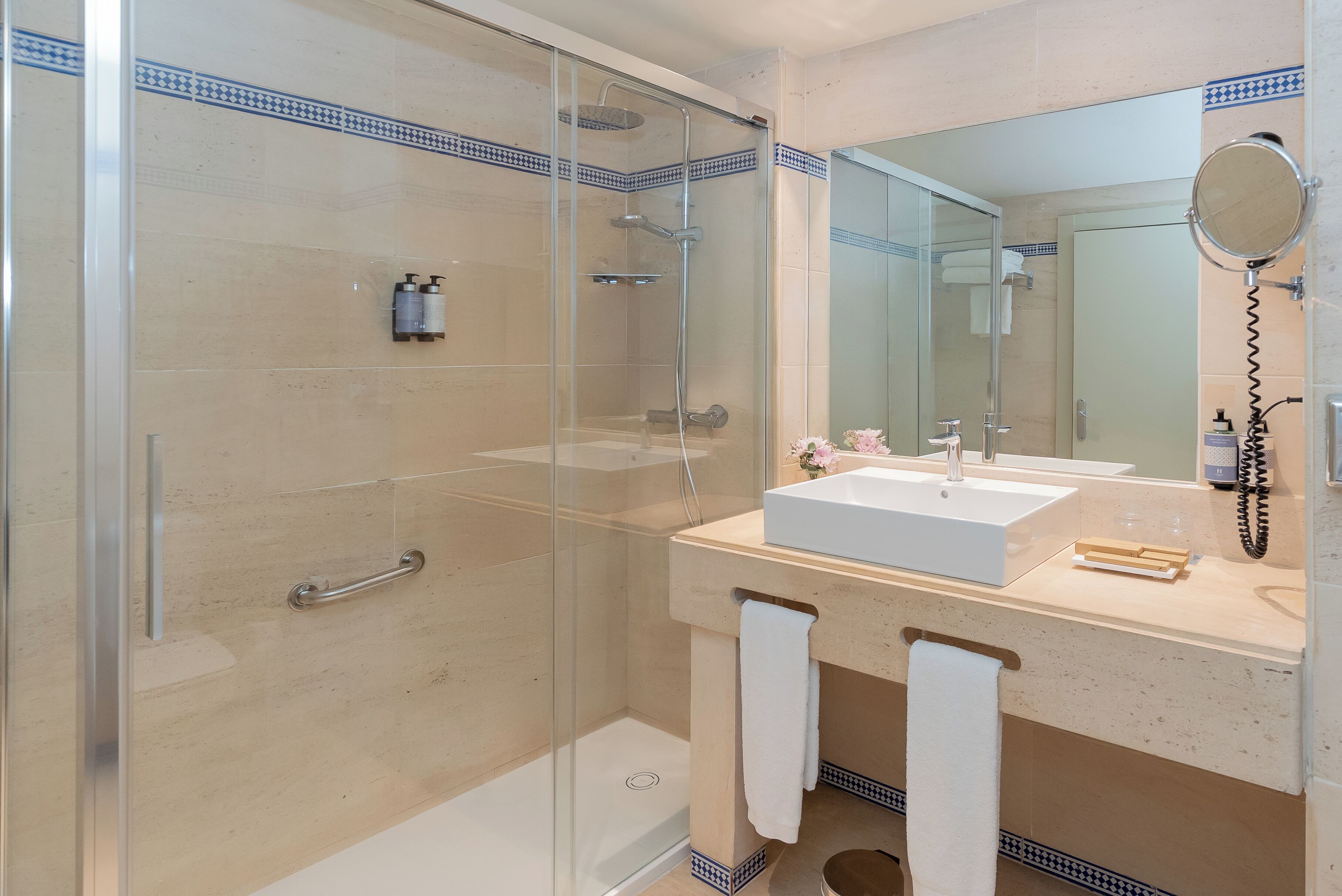 A modern bathroom with a glass-enclosed shower, a white sink, and a large mirror.
