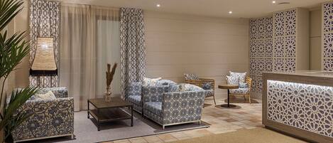 A modern living room with patterned sofas, a coffee table, and a decorative wall panel.