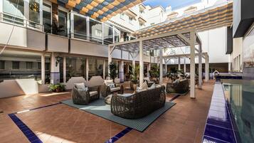 A spacious outdoor patio with multiple seating areas, a pool, and a covered walkway.