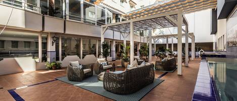 A spacious outdoor patio with multiple seating areas, a pool, and a covered walkway.
