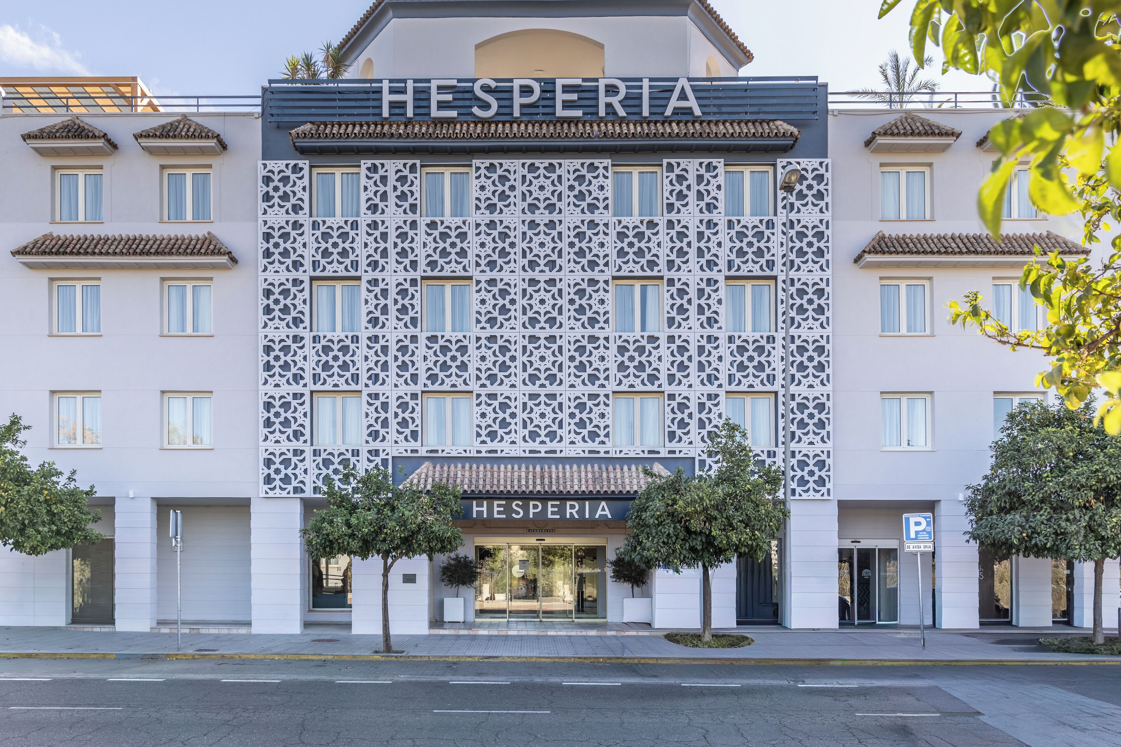 A hotel named HESPERIA with a modern facade, decorative lattice patterns, and a clear entrance.