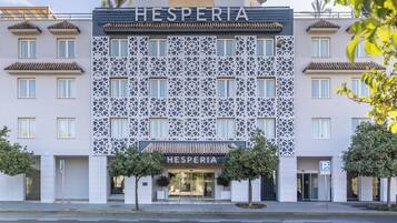 A hotel named HESPERIA with a modern facade, decorative lattice patterns, and a clear entrance.