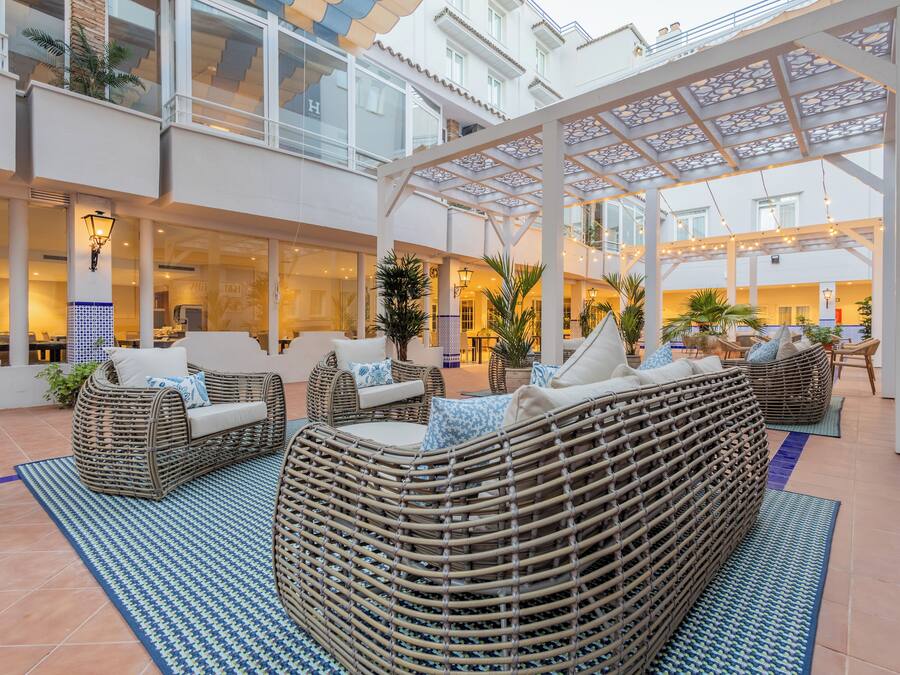 A spacious indoor area with wicker furniture, a glass ceiling, and a tiled floor.
