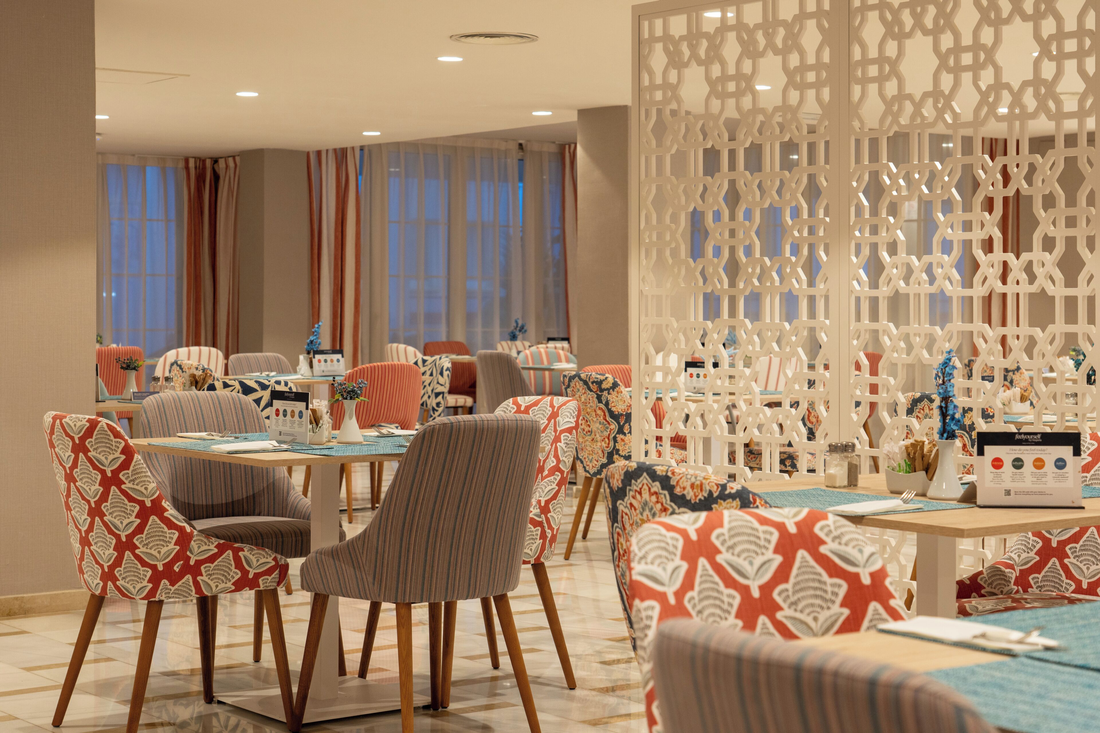 Habitación de hotel con varias zonas de estar, un separador decorativo y vistas a la ciudad.