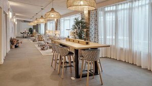 A modern dining area with a long table, multiple chairs, and hanging light fixtures.