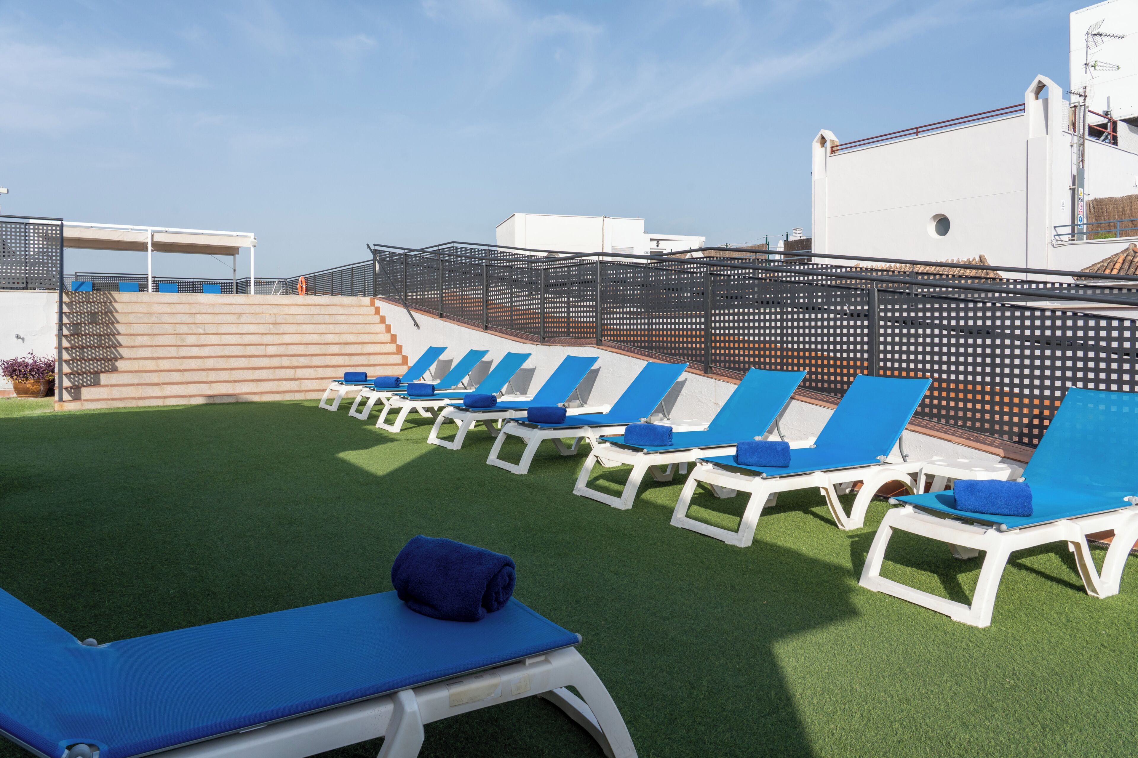En takterrass med en loungeyta, solstolar och en pool.