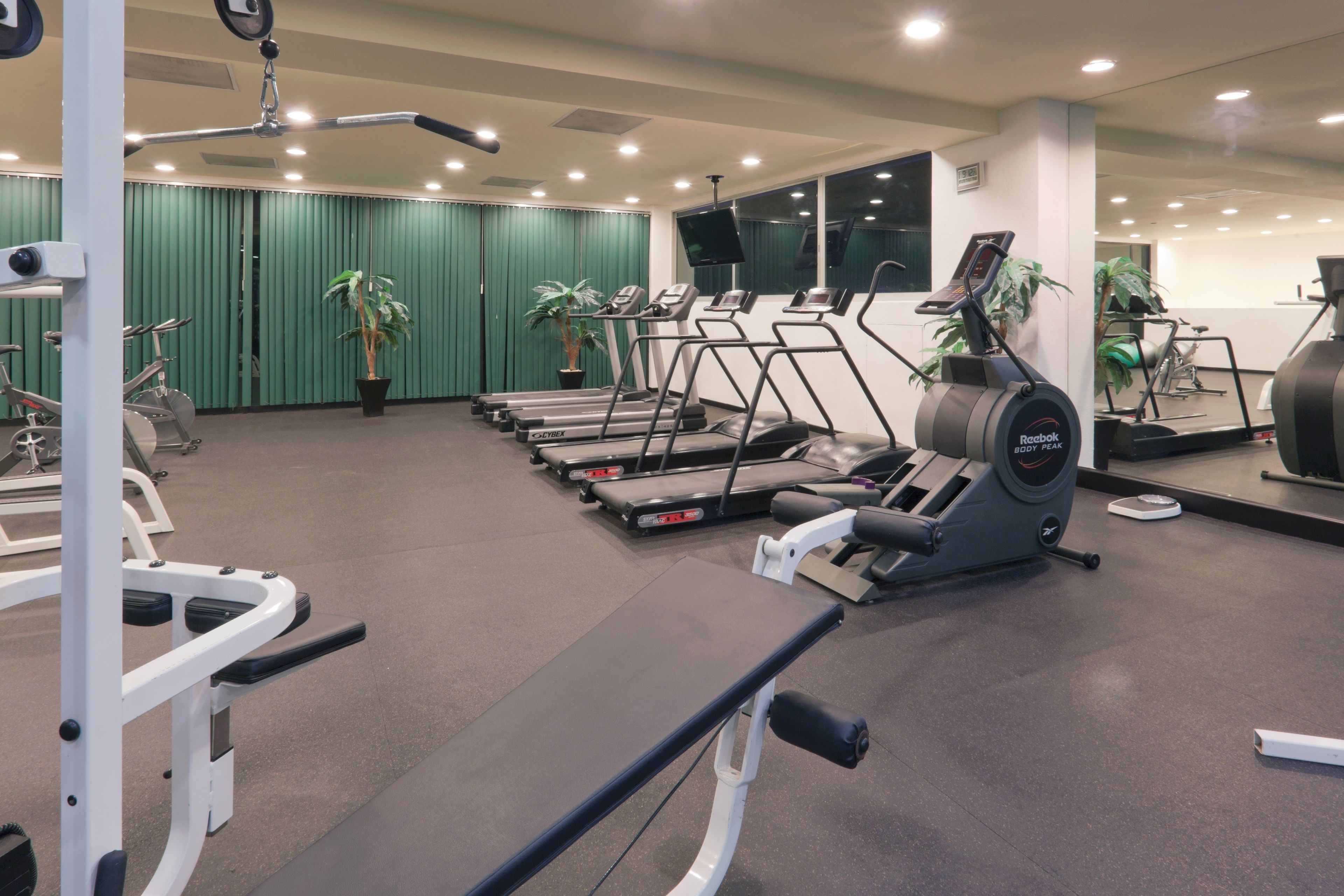 A gym with treadmills, weight machines, and exercise mats.