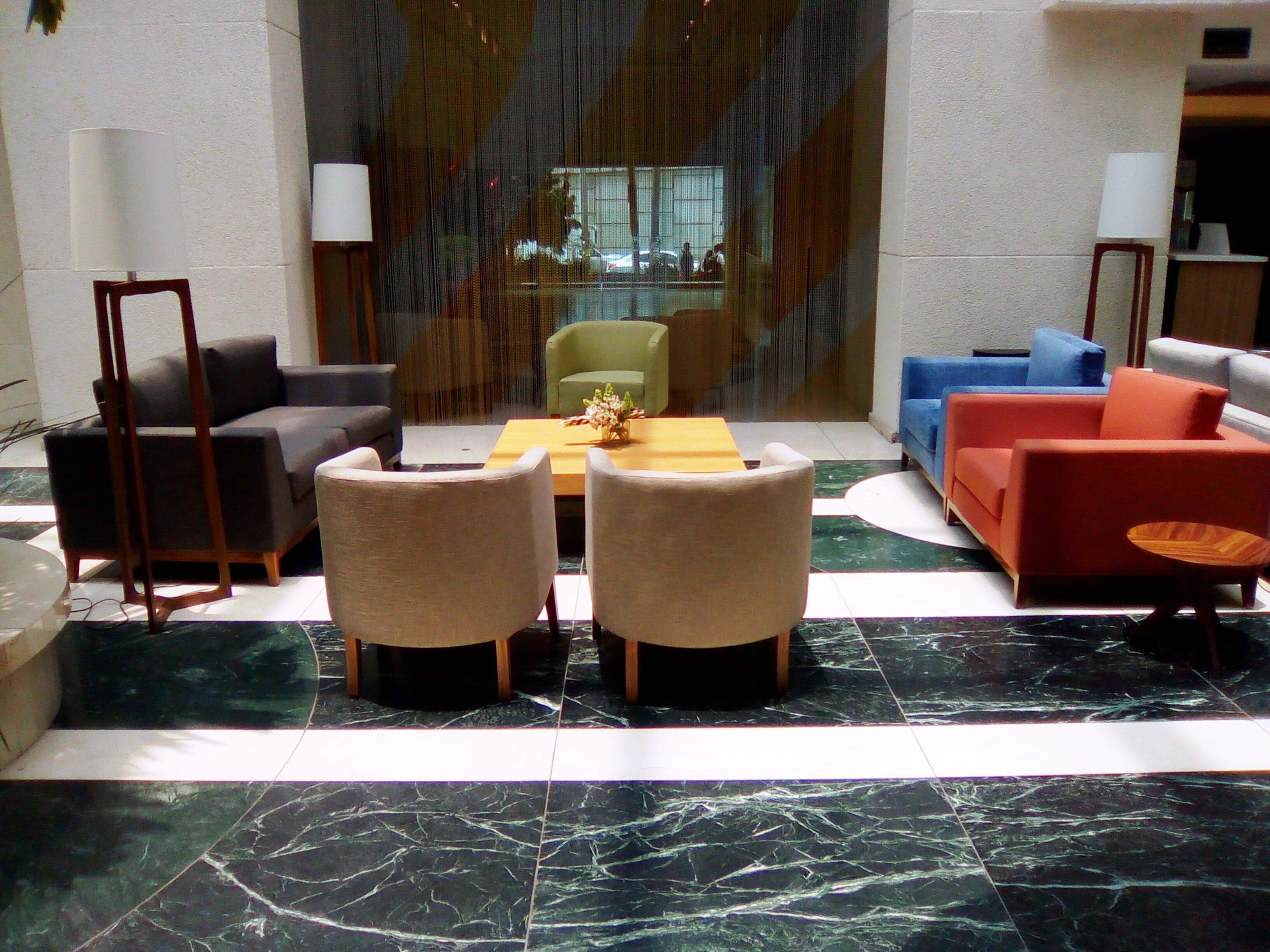 A lobby with a seating area featuring a table and chairs, a sofa, and a decorative plant.