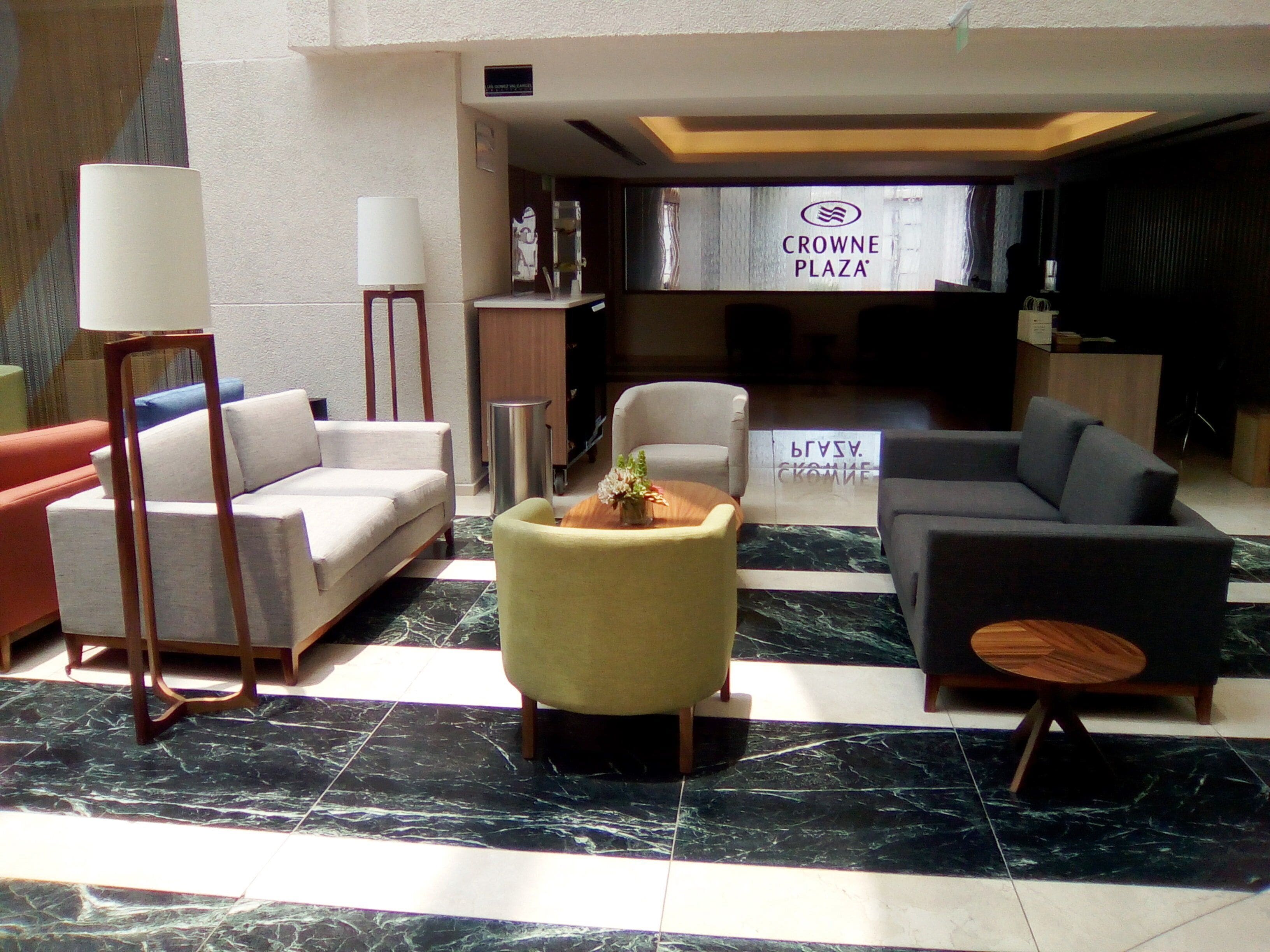 A lobby with a sofa, armchairs, a coffee table, and a reception desk.