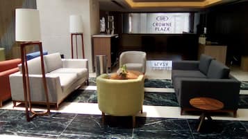 A lobby with a sofa, armchairs, a coffee table, and a reception desk.