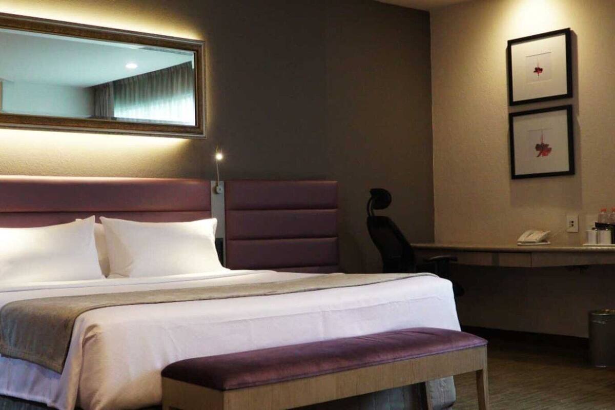 A hotel room with a large bed, a desk, and a chair.